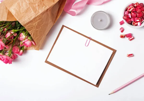 Blanco papier, kaars en rozen op de witte achtergrond — Stockfoto