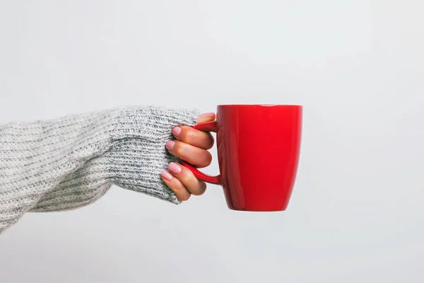 Mujeres mano en suéter acogedor sosteniendo una taza de café rojo . —  Fotos de Stock