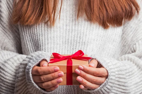 Vrouwelijke handen houden geschenkdoos met rood lint close-up. — Stockfoto