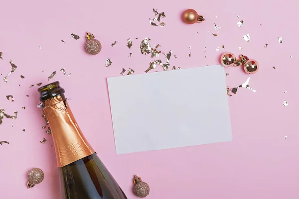 Blank paper card mock-up on the pink background with golden confetti and champagne bottle