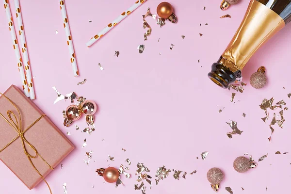 Champagne bottle, golden baubles and glitter and other festive decor on pink background. — Stock Photo, Image