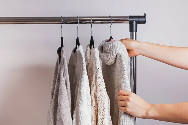 Mulher escolhendo uma das camisolas de malha quente de seu guarda-roupa minimalista . — Fotografia de Stock