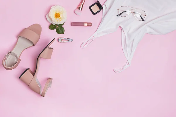 Accesorios femeninos con sandalias, top, lipstic y otros sobre fondo rosa , — Foto de Stock