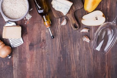 Tahta masada armut ve peynirli geleneksel İtalyan pilavı pişirmek için ham malzemeler.