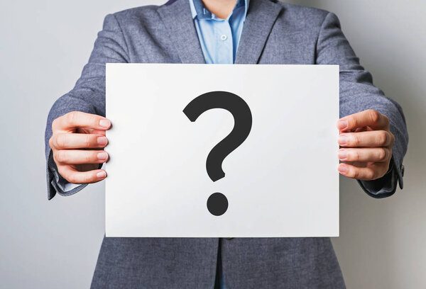 Young businessman holding white card with question mark on it