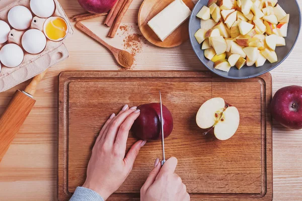Женские руки режут красное яблоко на столе — стоковое фото