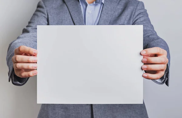 Homem de terno segurando um papel em branco — Fotografia de Stock