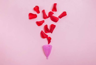 Kadınlar dönemi konsepti. Adet bardağı ve kırmızı gül yaprakları kanı simgeliyor..