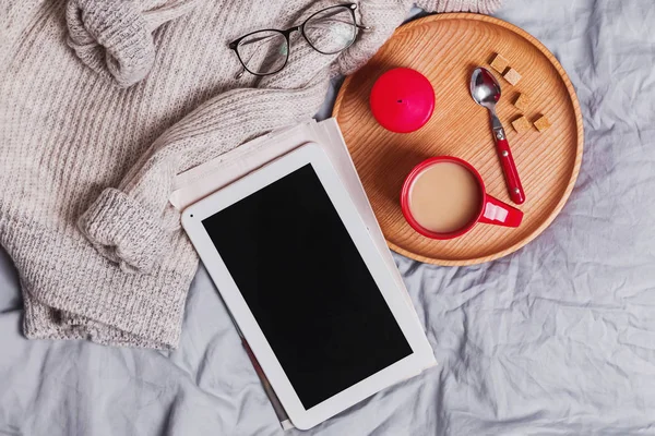 Boş tablet, bir fincan kahve, örgü süveter ve diğer küçük eşyalar.