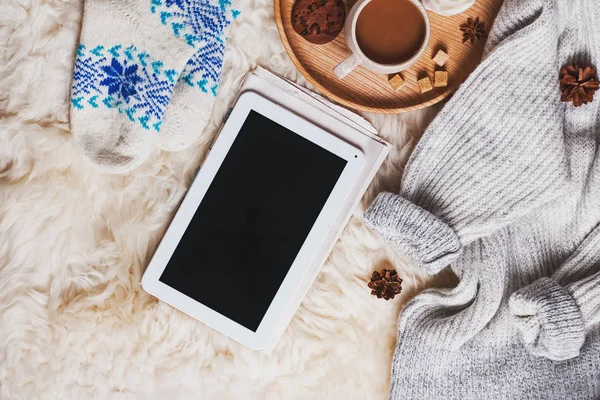 Tableta con pantalla en blanco, suéter caliente, calcetines y una taza de café en la piel — Foto de Stock