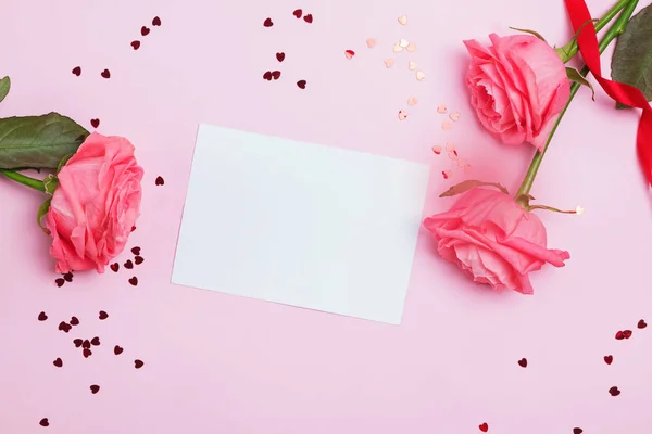 Empty greeting card on the pink table with roses nd small heart shaped confetti — Stock Photo, Image