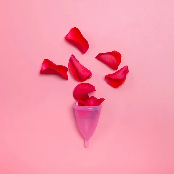 Womans period concept. Menstrual cup and red rose petals symbolizing blood.