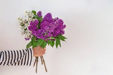 Bir demet güzel leylak çiçeğini tutan kadınlar.