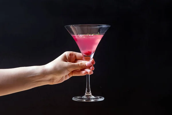 Feminine hand holding elegant glass with cranberry alcoholic cocktail