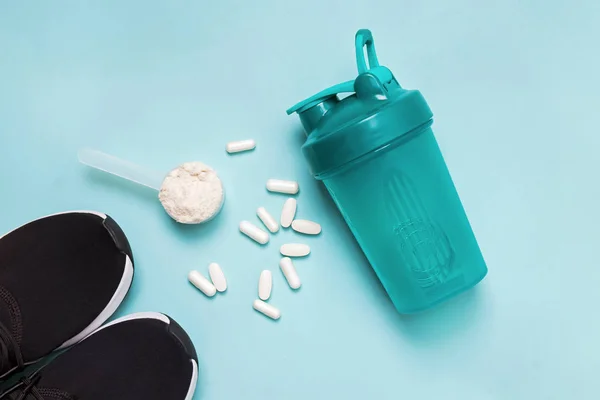 Polvo de proteína en una cuchara, coctelera, zapatillas de deporte y suplemento deportivo de dieta . — Foto de Stock