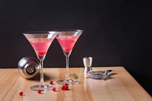 Martini glazen met cranberry cocktail en barmannen gereedschap op de houten tafel. — Stockfoto