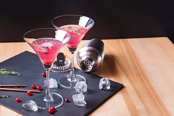 Vasos Martini con cóctel de arándano rojo y herramientas de barmen en la mesa de madera — Foto de Stock