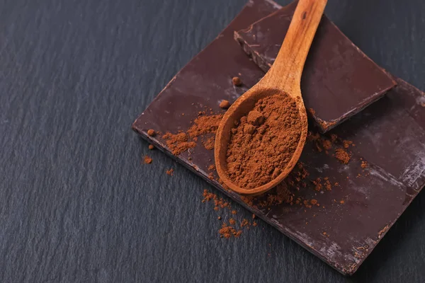 Barre de chocolat naturel et poudre de cacao dans une cuillère en bois close-up — Photo