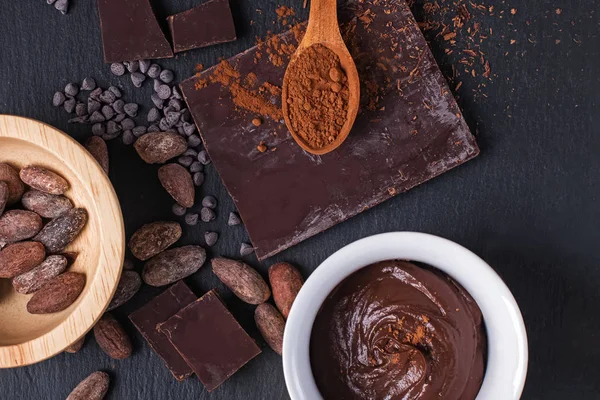 Frijoles de cacao, ganache de chocolate, trozos de polvo y chocolate sobre fondo negro , — Foto de Stock
