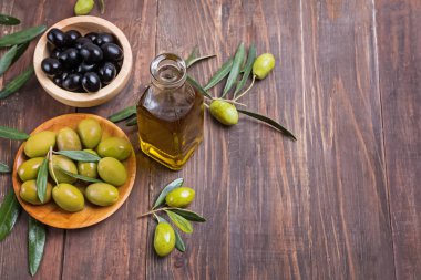 İki çeşit marine edilmiş zeytin, zeytin yağı ve ahşap masada dallar.