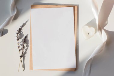 Kağıt, masanın üzerinde beyaz kurdele, lavanta ve kalp şeklinde mum ile gölgeli güneş ışığı şeklinde..