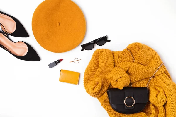 Женский наряд с желтым свитером, французский берет, сумка, солнцезащитные очки и другие предметы на белом фоне — стоковое фото