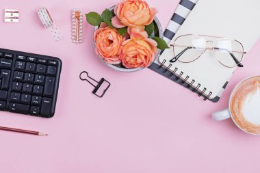 Styled women workplace with stationary, keybord, notapads and beautiful rose