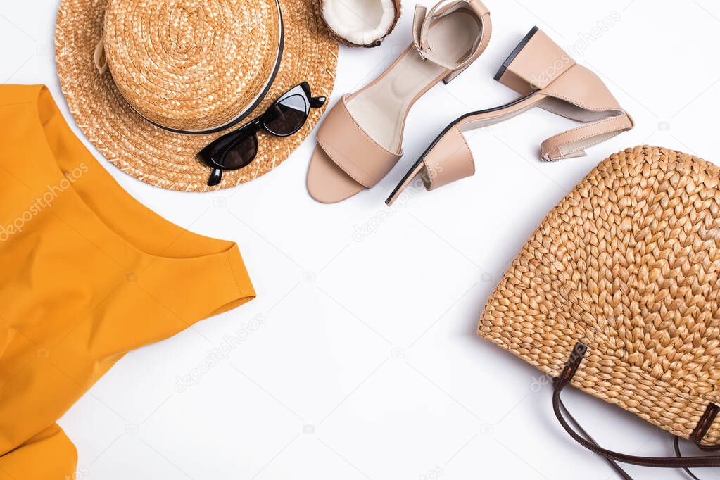 Feminine stylish summer outfit with sandals, straw hat and bag on the white table,