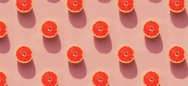 Grapefruit helften op roze achtergrond met natuurlijke lichte schaduwen. — Stockfoto
