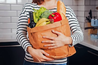 Unrecognizable woman holding bag full of fresh products