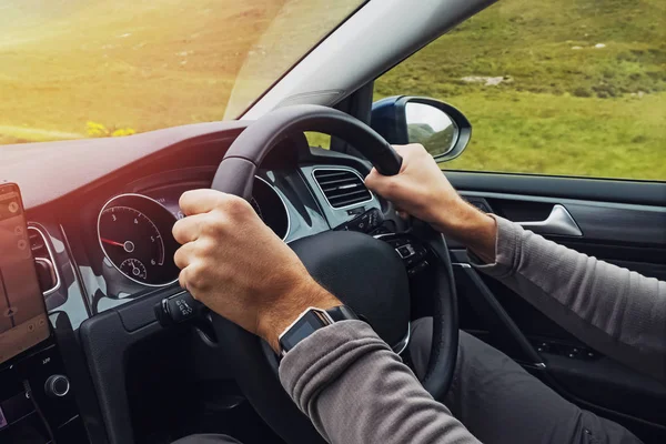 Man driving right hand car. Close-up shot of mans hands holding steering wheel.