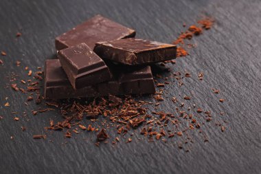 Pieces of chocolate bar on the black stone background