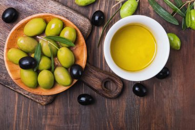 Olives and extra virgin olive oil in a bowl on wooden table