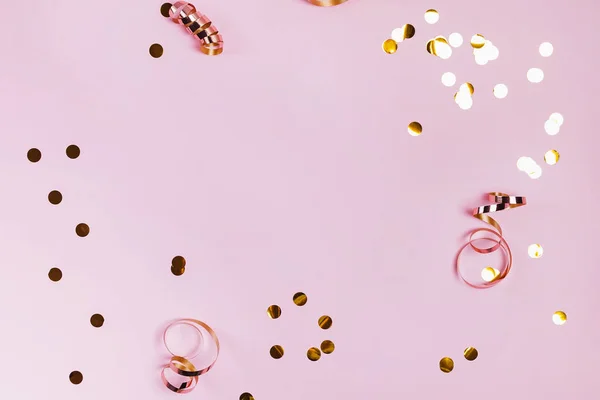 Błyszczące złote confeti i wstążki na różowym tle. — Zdjęcie stockowe