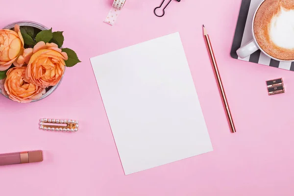 Mock-up de papel em branco na mesa rosa com rosas e artigos de papelaria — Fotografia de Stock