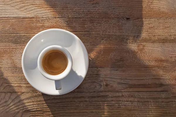 Чашка гарячої свіжої кави на дерев'яному столі в сонячний день — стокове фото