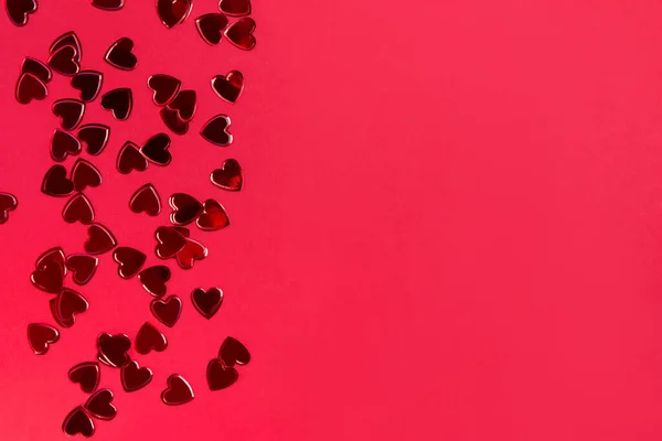 Small red heart shaped confetti on red background — Stock Photo, Image