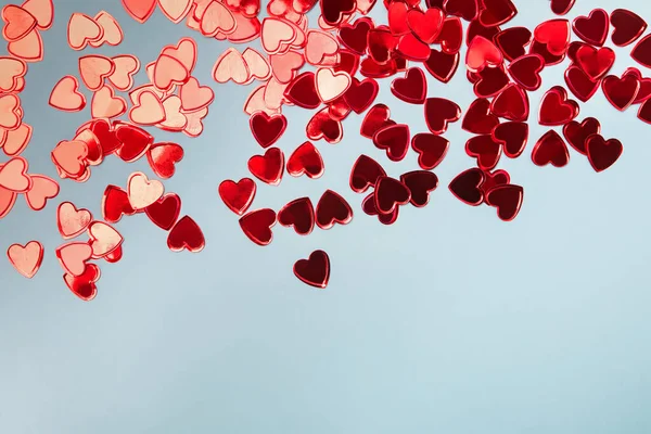 Small red heart shaped confetti on blue background, — Stock Photo, Image