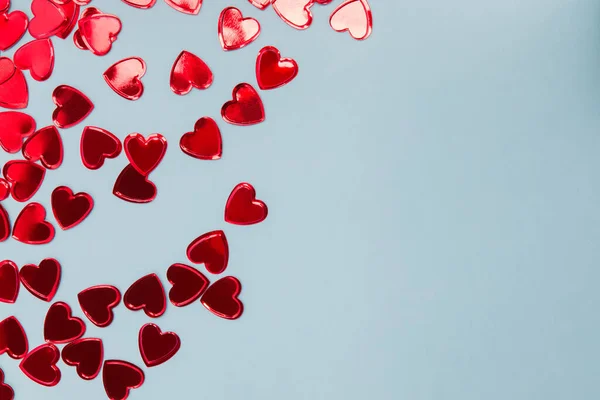 Pequeño confeti rojo en forma de corazón sobre fondo azul , — Foto de Stock