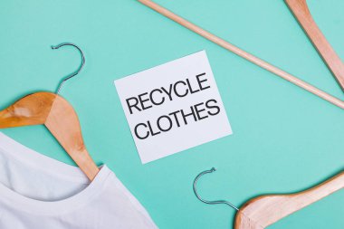 Ahşap askılarda beyaz tişörtler Ponk arka planında uzanır, üst manzara