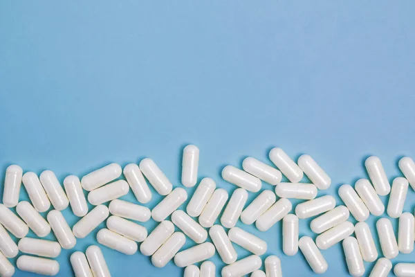 Белые медицинские таблетки на синем фоне с копировальным пространством . — стоковое фото