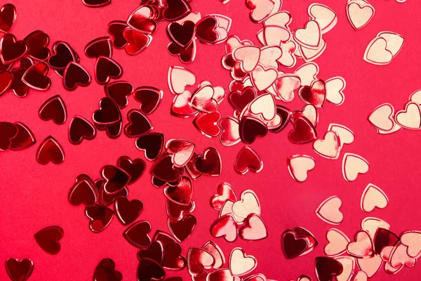 Coeurs brillants de paillettes de feuille sur fond rouge — Photo