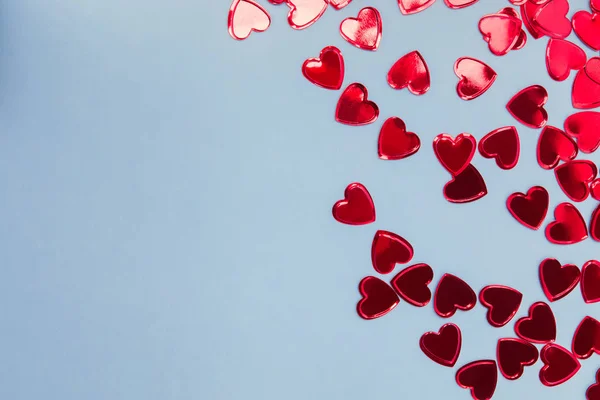 Small red heart shaped confetti on blue background, — Stock Photo, Image