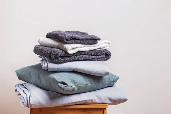 Pile of clean folded home textile items near the white wall. — Stock Photo, Image