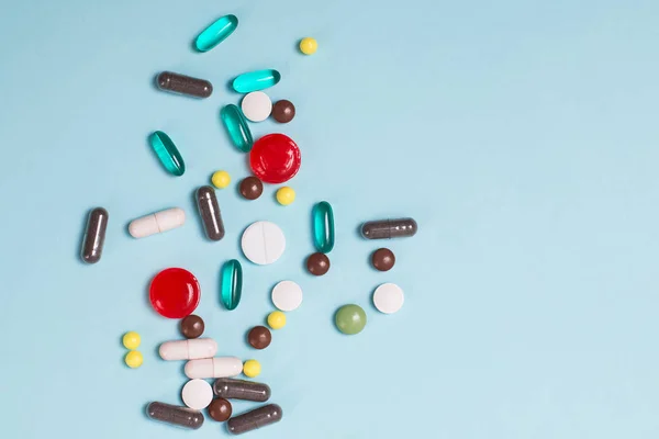 Различные разноцветные таблетки и таблетки на синем фоне . — стоковое фото