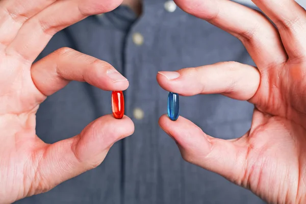 Руки крупным планом предлагают красные и синие таблетки — стоковое фото