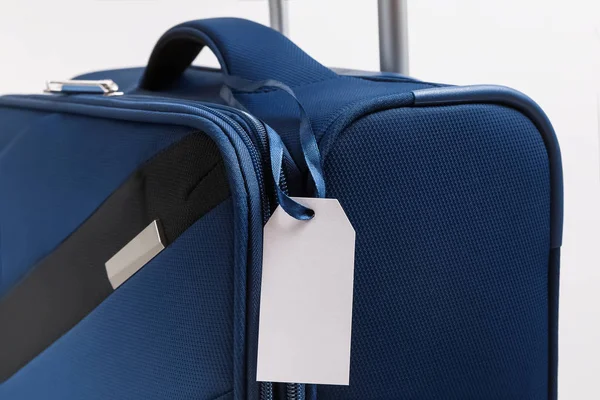 Etichetta vuota del bagaglio di carta sulla valigia blu — Foto Stock