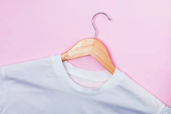 White shirt on wooden hanger lying on pastel pink background — Stock Photo, Image