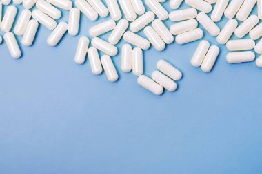 Mavi arka planda bir sürü beyaz ilaç var.