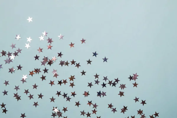 Slavnostní konfety ve tvaru hvězdy roztroušené na pastelově modrém pozadí — Stock fotografie